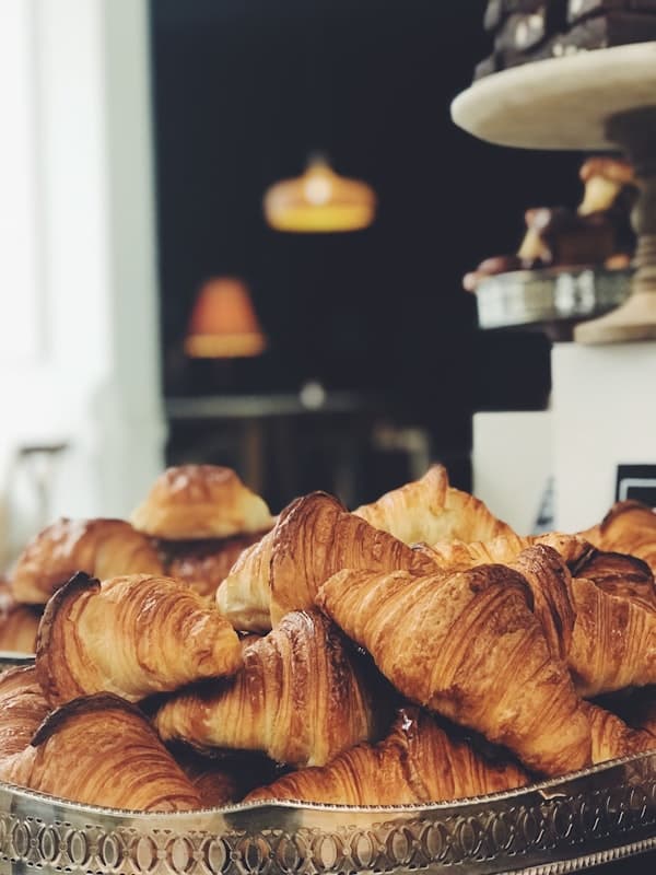 A display of pastries behind glass — croissants, danishes, and morning buns glistening