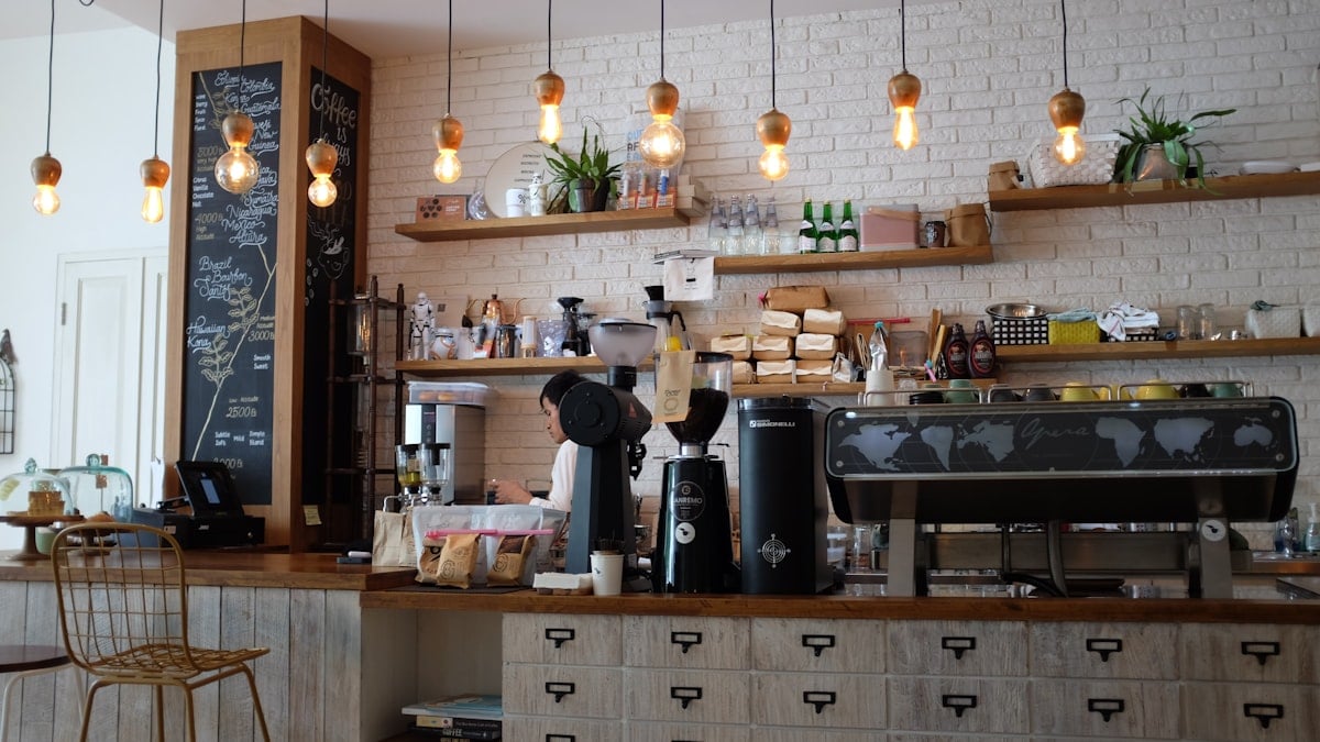 The Ember & Grain shopfront on a sunny morning, chalkboard sign outside, bicycles leaning against the wall