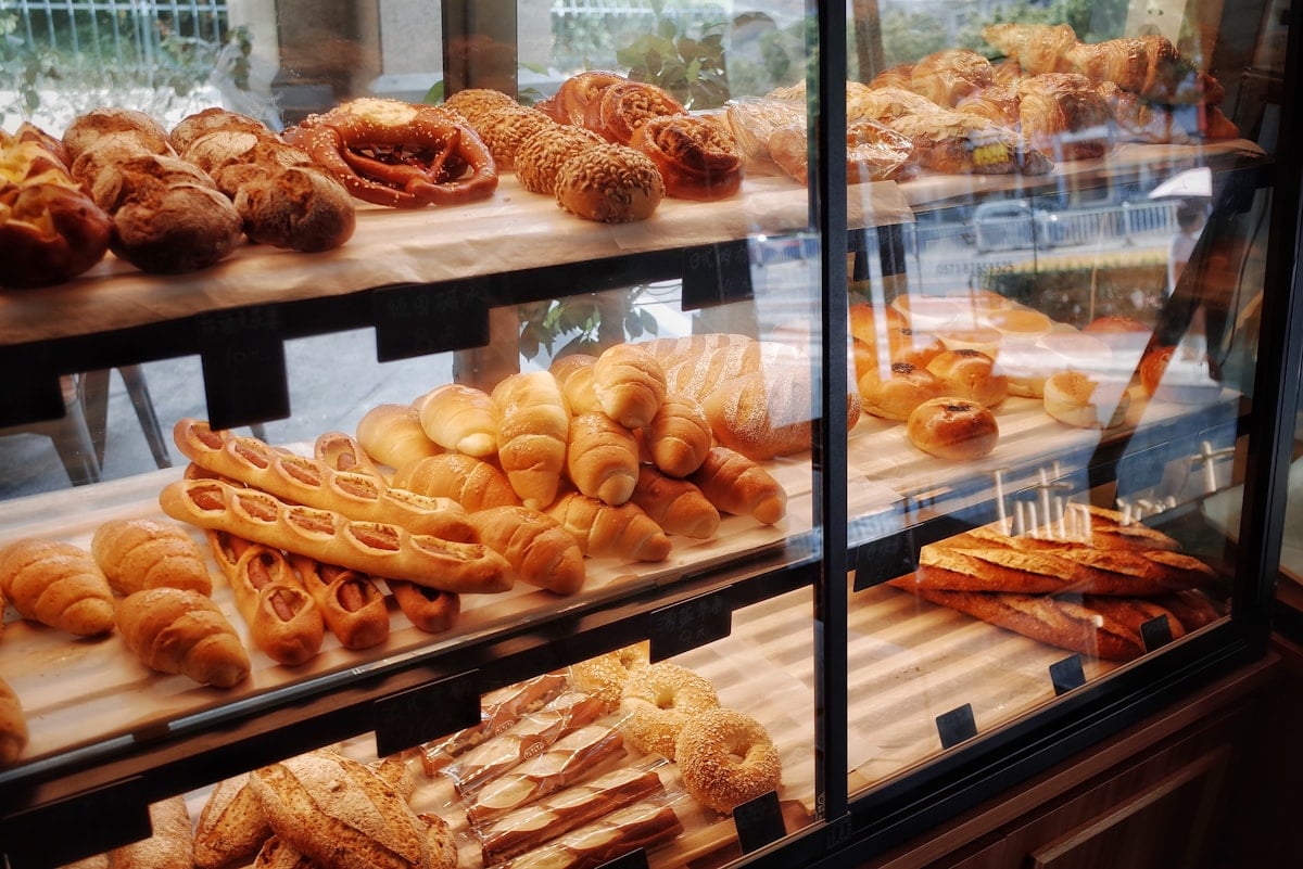 Paper-wrapped sourdough loaves lined up on a shelf behind the counter, handwritten name tags attached