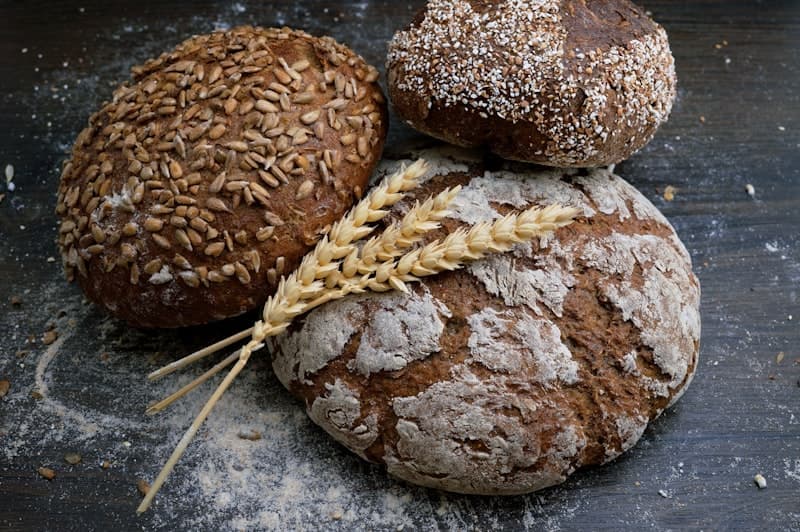 A round country sourdough loaf with a deeply scored wheat-ear pattern, dark crackling crust, dusted with flour